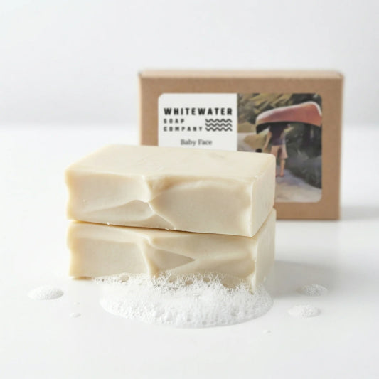 Two bars of soap stacked with a box from Whitewater Soap Company in the background.