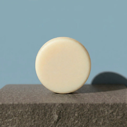 Beige conditioner bar on a textured surface with a light blue background