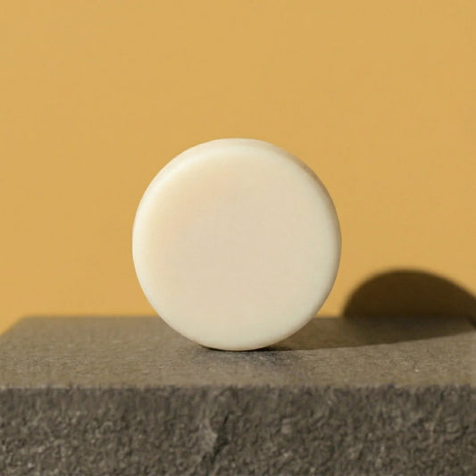 White conditioner bar  on a textured surface with a yellow background