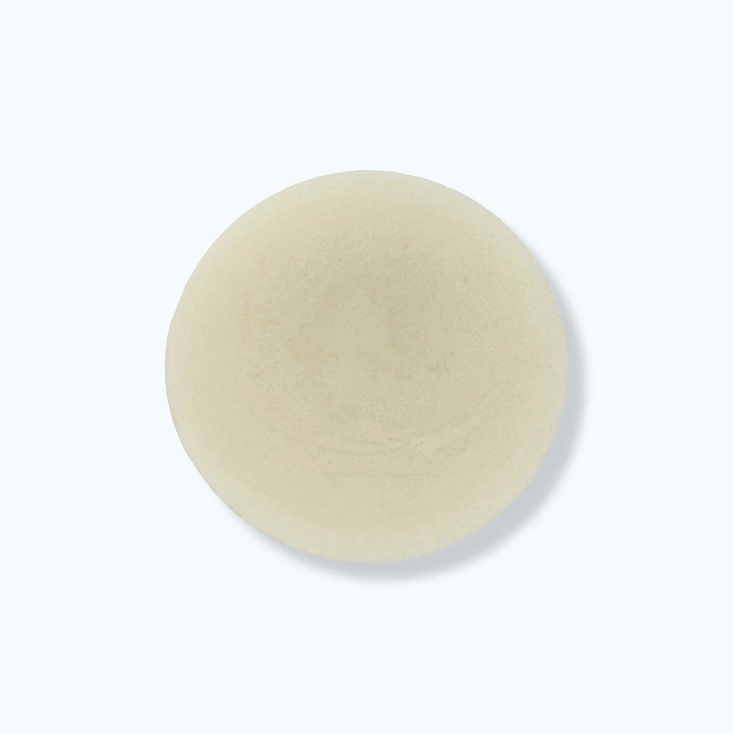 Round beige solid hair conditioner bar on a white background