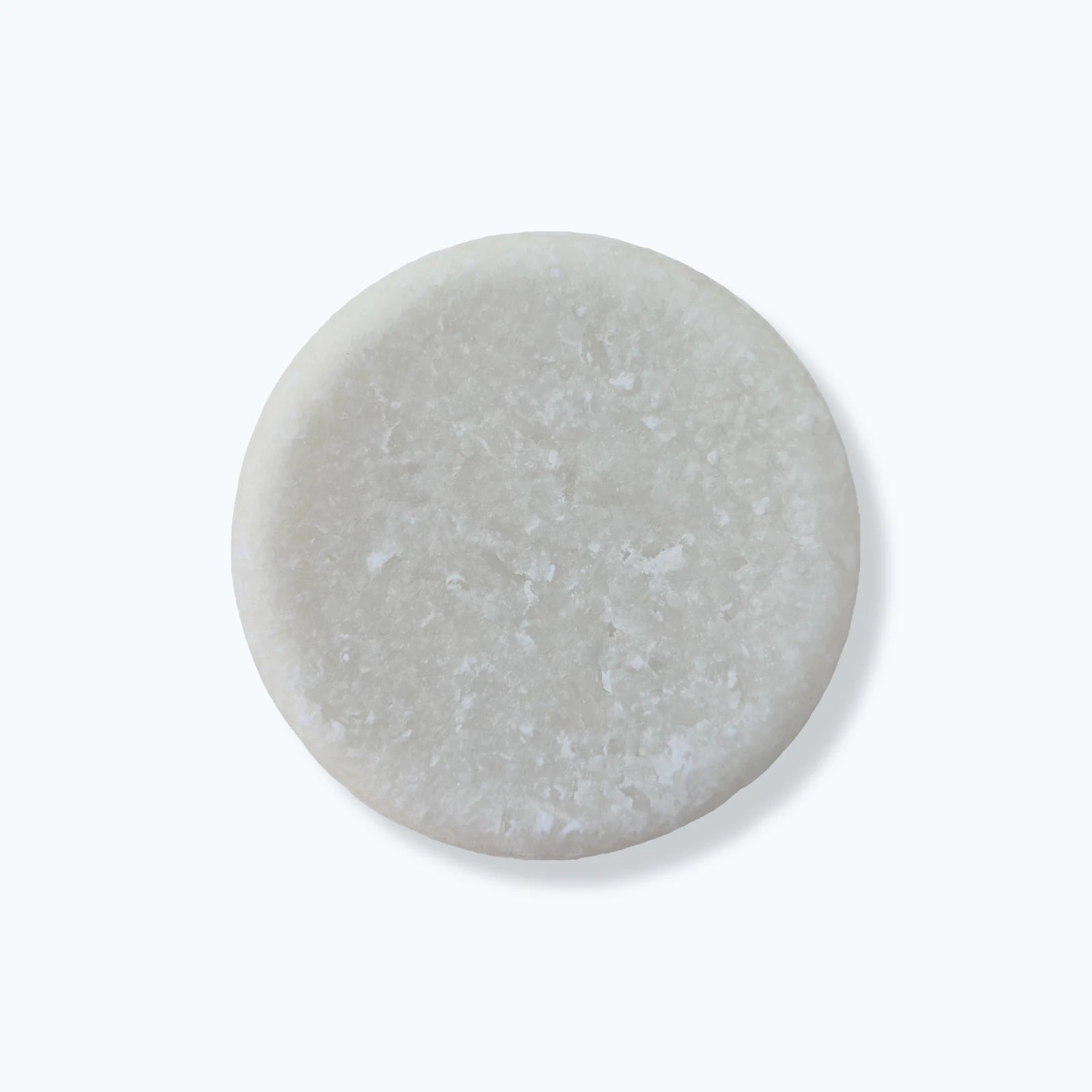 Round white solid shampoo bar on a white background