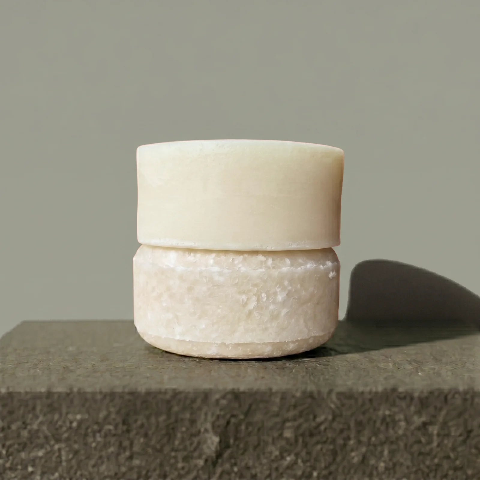 Shampoo and conditioner bars stacked on a stone surface