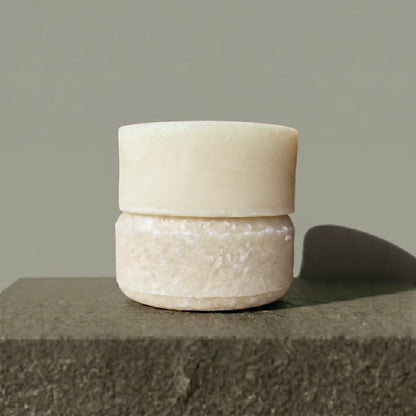 Shampoo and conditioner bars stacked on a stone surface