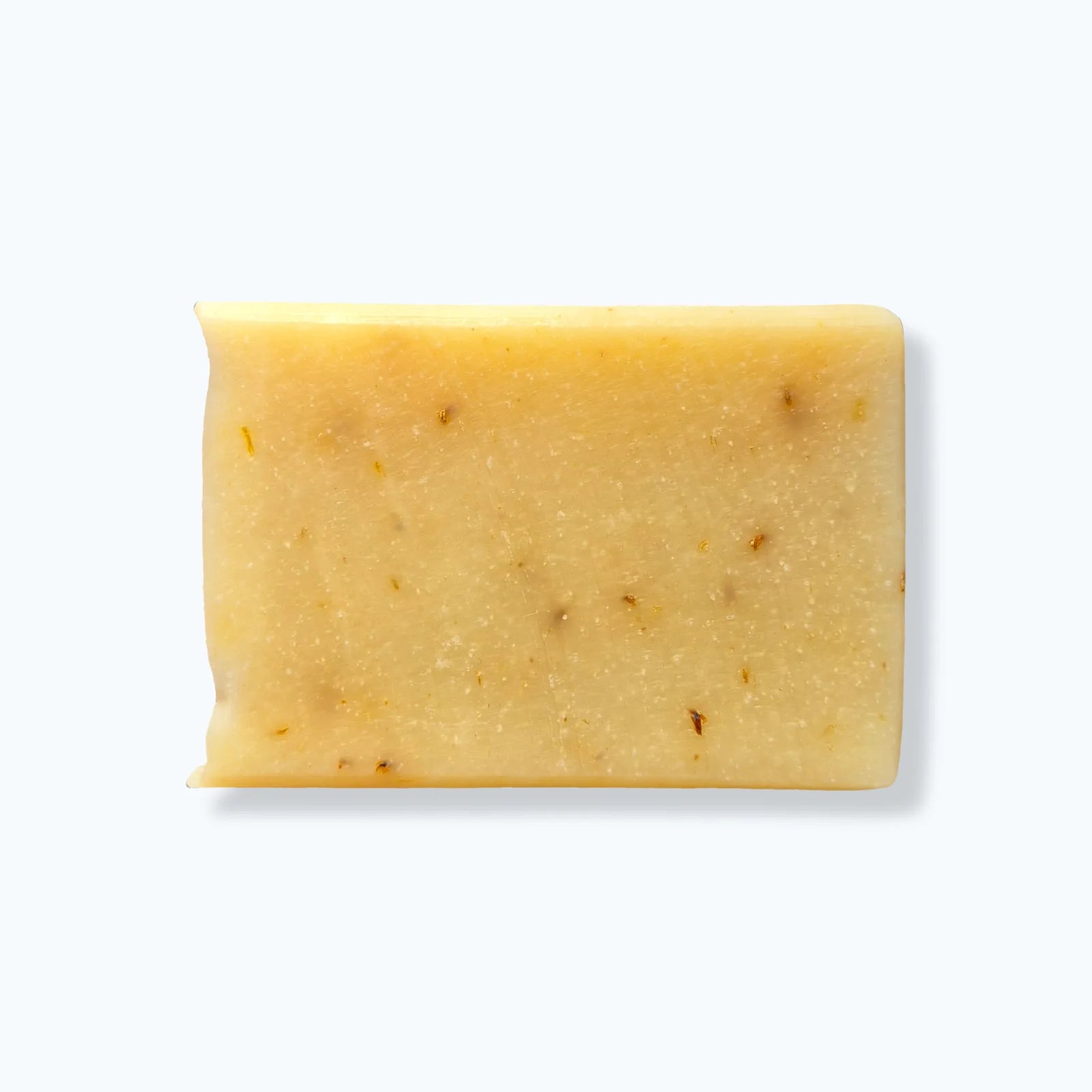 Bar of soap with specks of dandelion seeds on a white background
