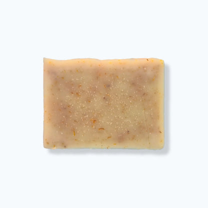 Bar of soap with calendula petals on a white background